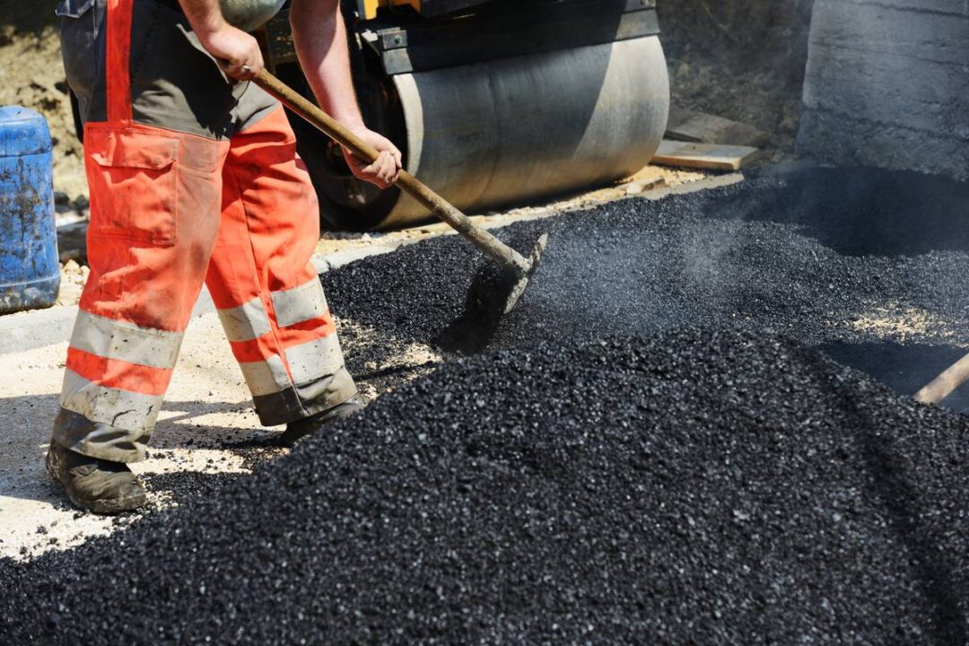 Men hard working on asphalting road with shovels